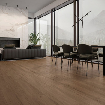 Houten vloeren beslaan een moderne woon- en eetkamer, met een grijze bank, planten, grote ramen en een eigentijdse lamp.
