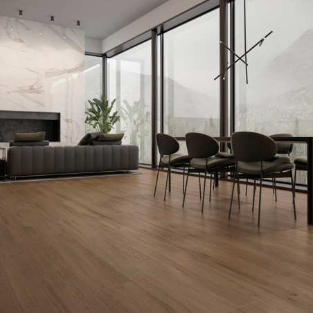 O piso de madeira abrange uma moderna área de estar e jantar, com sofá cinza, plantas, janelas grandes e luminária contemporânea