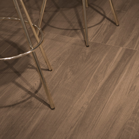 Wooden-textured ceramic tiles create a warm, natural aesthetic, where metal chair legs rest, casting soft shadows in a muted int