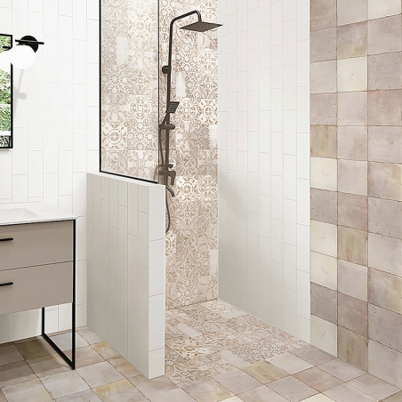 Uma área de chuveiro com intrincados azulejos com padrões bege e creme tem um moderno chuveiro preto. É cercado por azulejos ver