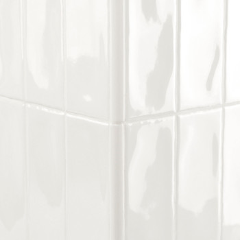 Les carreaux blancs brillants, réfléchissant la lumière, forment un angle vif dans un mur propre et bien éclairé.