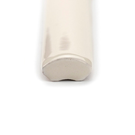 Una moldura de cerámica brillante de color crema se encuentra horizontalmente y termina en un borde redondeado y liso. Está colo Una moldura de cerámica brillante de color crema se encuentra horizontalmente y termina en un borde redondeado y liso. Está colo