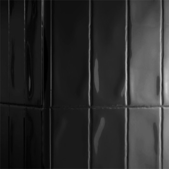 Les carreaux noirs brillants réfléchissent la lumière verticalement, créant une surface élégante et moderne dans un espace minim