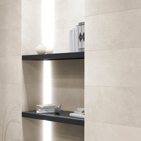 Beige keramische tegels bedekken een muur met ingebouwde verzonken planken. Objecten zijn onder meer decoratieve boeken, vazen ​