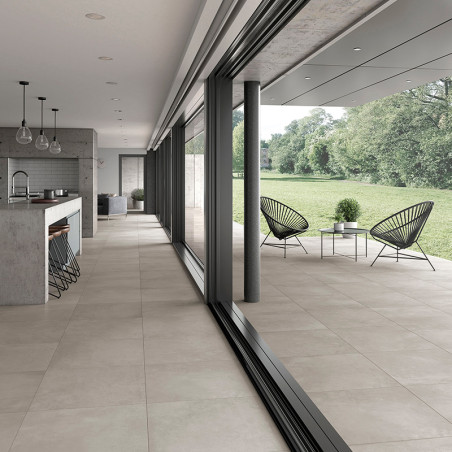 Les carreaux de couleur crème s'étendent d'une cuisine ouverte, en passant par des portes coulissantes en verre, jusqu'à un pati