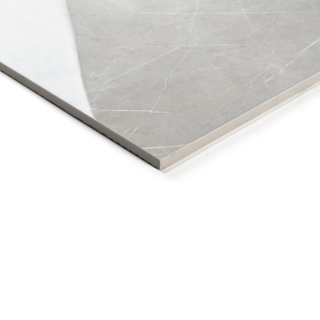 Un azulejo gris liso, rectangular con sutiles vetas blancas descansa sobre una superficie blanca, reflejando la luz para una apa