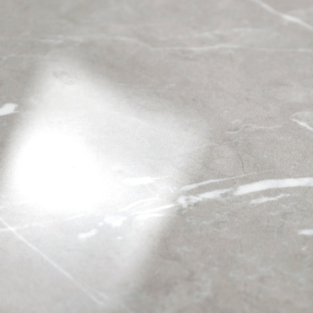 Un carreau de marbre lisse et brillant reflète une lumière vive. La surface présente de subtiles veines grises et blanches, sugg