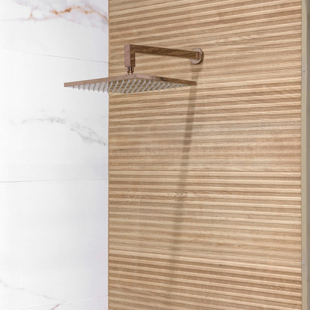 Une pomme de douche carrée en métal s'étend d'un mur, contre du bois à rayures verticales et des carreaux de marbre blanc adjace Une pomme de douche carrée en métal s'étend d'un mur, contre du bois à rayures verticales et des carreaux de marbre blanc adjace