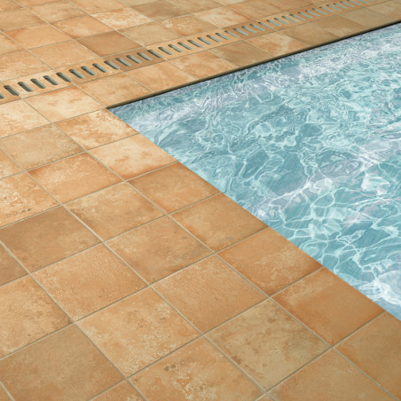 azulejos de terracota rodean una piscina azul brillante, con patrones de agua visibles. Una rejilla de metal se encuentra al lad azulejos de terracota rodean una piscina azul brillante, con patrones de agua visibles. Una rejilla de metal se encuentra al lad