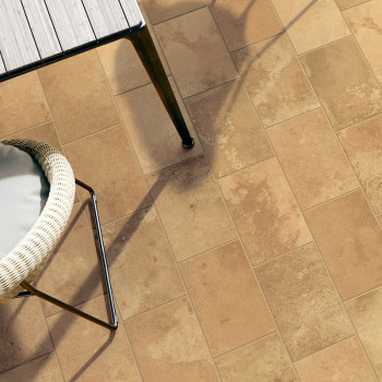 Les carreaux de céramique beige forment un sol à motifs. une chaise tressée avec un siège rembourré se tient à côté d'une table 