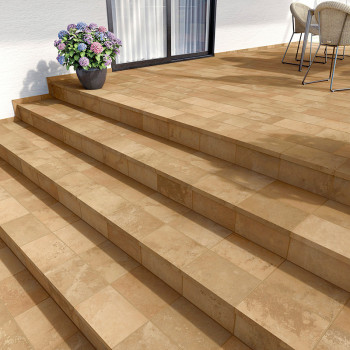 Een reeks beige terracottategels bedekt een terras en trappen. Naast glazen deuren staat een potplant, met stoelen ernaast.