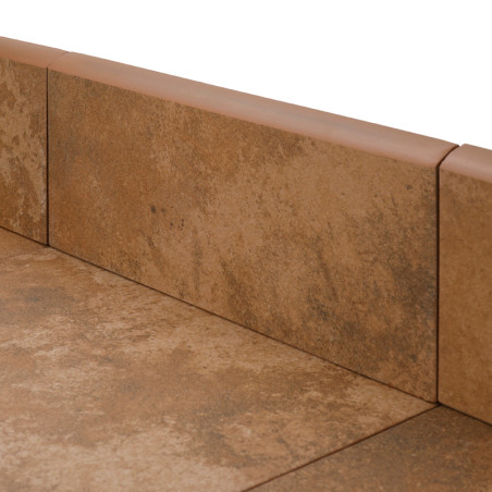 Les plinthes en céramique marron sont soigneusement disposées dans un coin, créant un joint homogène entre le mur et le sol d'une pièce.