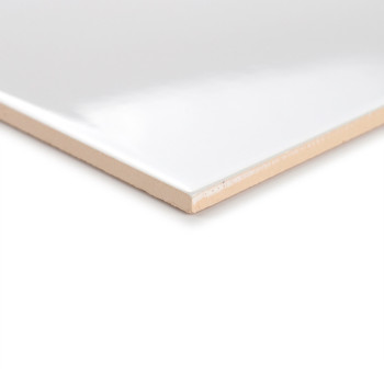 Un azulejo blanco brillante descansa en ángulo, resaltando su superficie lisa y su borde beige, sobre un fondo neutro.