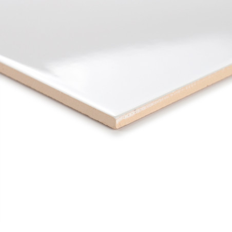 Un azulejo blanco brillante descansa en ángulo, resaltando su superficie lisa y su borde beige, sobre un fondo neutro.
