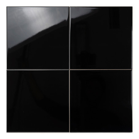 Cuatro azulejos negros brillantes reflejan la luz, dispuestos en un patrón de cuadrícula cuadrada, sobre un fondo blanco liso.