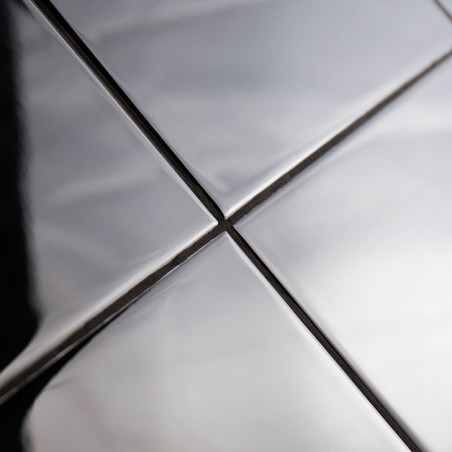 Four shiny, metallic tiles are aligned in a grid, reflecting light and shadows. They form intersecting lines, suggesting a moder