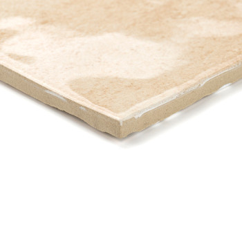 A beige ceramic tile with a smooth, glossy surface is resting on a white background. The tile shows subtle marbling patterns.
