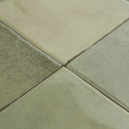 Cuatro azulejos cuadrados de cerámica brillante encajan a la perfección, coloreados en tonos apagados de verde y beige, bajo una