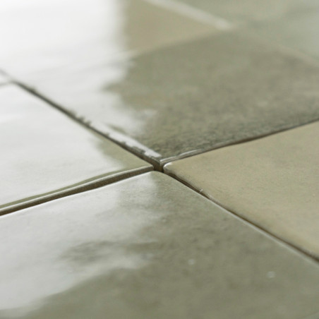 Les carreaux carrés verts brillants réfléchissent la lumière, créant une surface brillante et lisse. Ils sont disposés uniformém