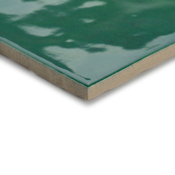 A glossy, green ceramic tile with a polished surface reflects light. the tiles edges reveal a tan base, suggesting durability.