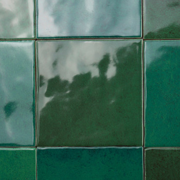 Les carreaux verts recouvrent une surface, reflétant des ombres et une lumière vagues, créant un motif brillant et irrégulier au