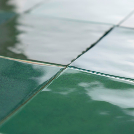 Grüne Keramikfliesen bilden ein Gittermuster, reflektieren das Licht mit einer glänzenden Oberfläche und erzeugen eine glatte, l