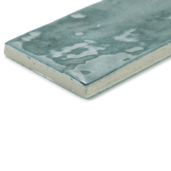 Le carreau de céramique rectangulaire avec une surface sarcelle foncée brillante et marbrée repose à plat sur un fond blanc, met