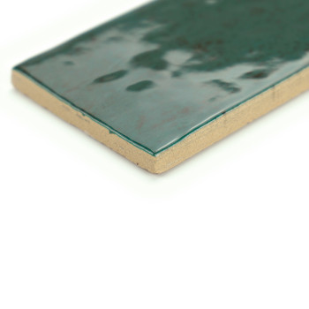 Azulejo cerámico rectangular con una superficie verde brillante y moteada, descansa sobre un fondo blanco liso, mostrando su bor