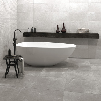 Une élégante baignoire blanche repose sur un sol carrelé gris entouré d'un décor minimaliste, comprenant un banc en bois avec de