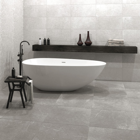 Une élégante baignoire blanche repose sur un sol carrelé gris entouré d'un décor minimaliste, comprenant un banc en bois avec de