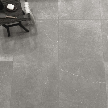 Des carreaux de pierre grise recouvrent un sol, présentant de subtiles veines blanches. Sur le côté, une table en bois contient 