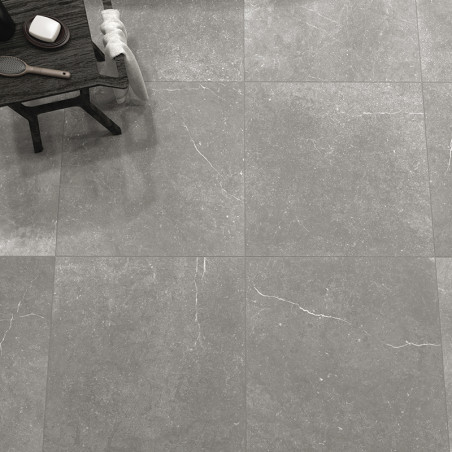 Des carreaux de pierre grise recouvrent un sol, présentant de subtiles veines blanches. Sur le côté, une table en bois contient 