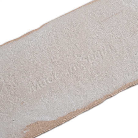 Un carreau rectangulaire affiche le texte en relief « Made in Spain ». Le carreau a une surface texturée beige et des bords robu