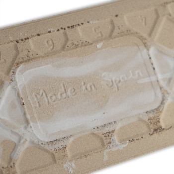 Auf einer beigen Fliese ist in einem rechteckigen Bereich der Text „Made in Spain“ eingeprägt. Die umliegenden Zahlen „9“ und „7