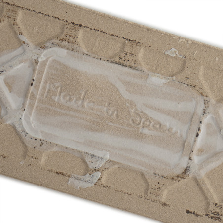 Die beige Keramikfliese weist ein erhabenes geometrisches Muster auf. Der geprägte Text „Made in Spain“ ist inmitten der Textur Die beige Keramikfliese weist ein erhabenes geometrisches Muster auf. Der geprägte Text „Made in Spain“ ist inmitten der Textur