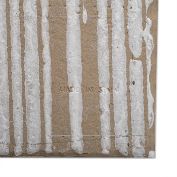 Azulejo marrón con patrones de goteo blancos verticales. En el centro lleva grabado el texto `MADE IN SPAIN`. El entorno es llan