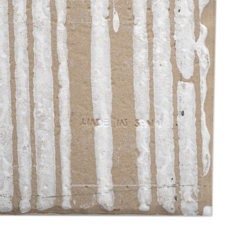 Vertical white drips adorn a textured, brown tile background. The text `MADE IN SPAIN` is subtly stamped into the surface.