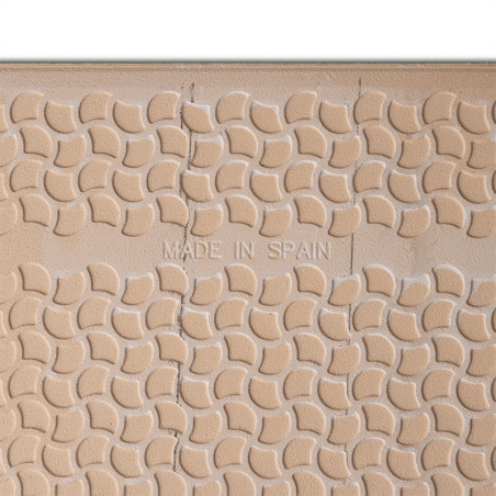 Un azulejo texturizado muestra un patrón repetitivo de formas curvas. El texto centrado dice `MADE IN SPAIN`, rodeado por una su