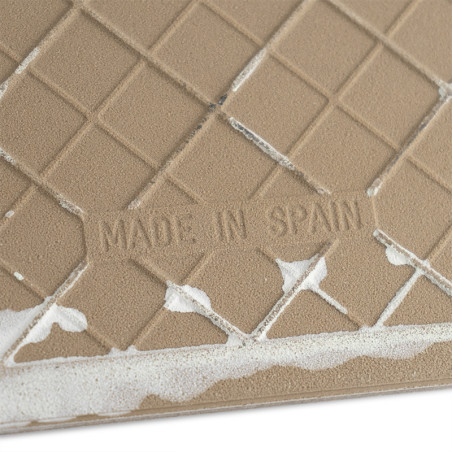 Surface carrelée avec motif quadrillé en relief, avec le texte « MADE IN SPAIN ». Les bords présentent des traces d'adhésif blan