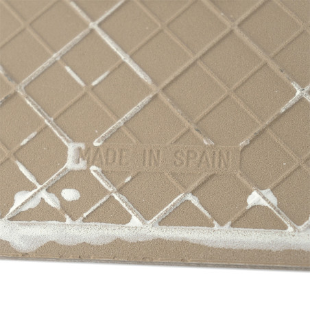 Un azulejo beige presenta un patrón de cuadrícula texturizado con líneas blancas que se cruzan en su superficie. El texto lee: `