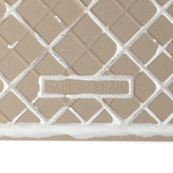 Un carreau de céramique beige texturé affiche un motif de grille géométrique. Le texte « MADE IN SPAIN » est gravé dans un cadre
