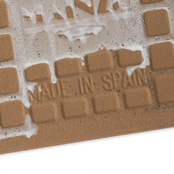 Ladrilho quadrado texturizado com padrão de grade em relevo. O texto diz "MADE IN SPAIN". Um resíduo manchado cobre parte do des