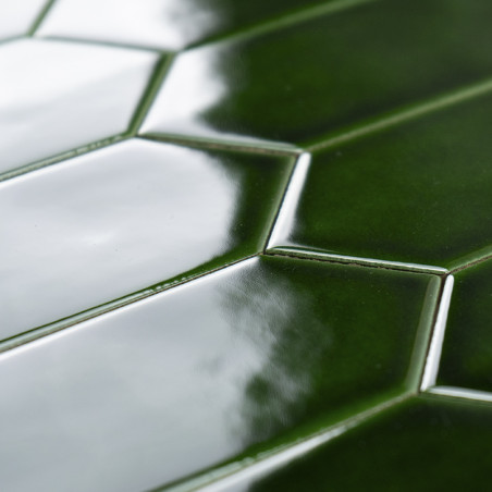 Los azulejos de cerámica de color verde brillante forman un patrón en espiga que refleja la luz en un ambiente interior luminoso Los azulejos de cerámica de color verde brillante forman un patrón en espiga que refleja la luz en un ambiente interior luminoso