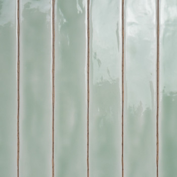 Azulejos rectangulares brillantes de color verde pastel alineados verticalmente. reflejar la luz, creando ligeras variaciones de