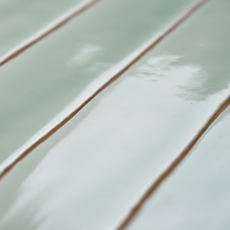 Azulejos verde azulado rectangulares brillantes alineados en paralelo. reflejando la luz, creando una superficie lisa y limpia c