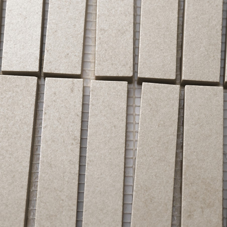 Los azulejos rectangulares de color beige están dispuestos en filas verticales, alineados estrechamente sobre un respaldo de mal