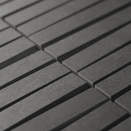 Los azulejos rectangulares de color gris oscuro se alinean en filas paralelas, creando un patrón rítmico. Los azulejos forman un