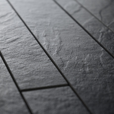 Les carreaux rectangulaires texturés avec une surface rugueuse semblable à de la pierre forment un motif organisé. Ils sont rapp