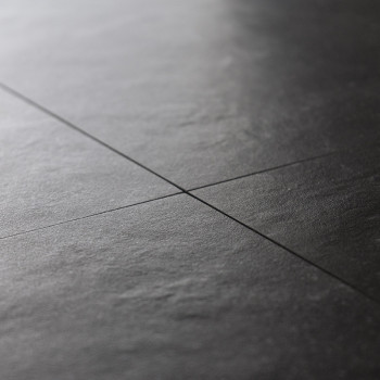 Dark stone tiles, aligned in a grid pattern, create a smooth, matte surface with subtle texture, conveying a modern, minimalist 