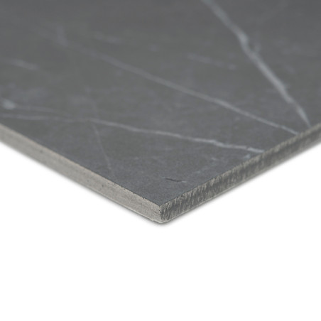 De tegel heeft een glad, donkergrijs oppervlak met subtiele witte nerven. Het heeft een afgeschuinde rand en is geplaatst tegen 